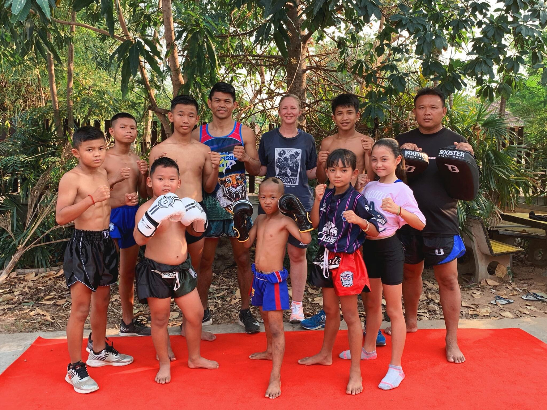 Boom and Frances standing with the coaches and children of Wor. Watthana outside the gym.